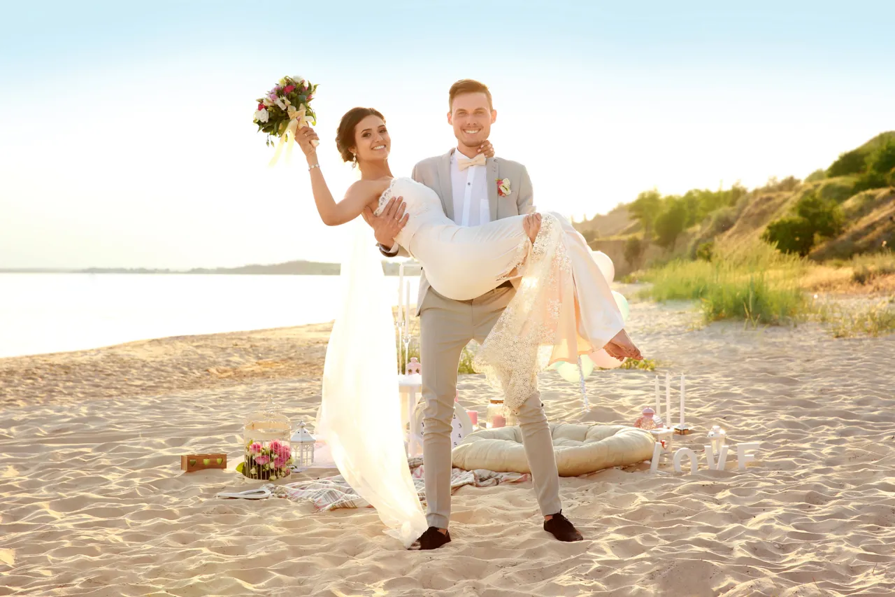 A newly married couple celebrating together on a sunlit beach